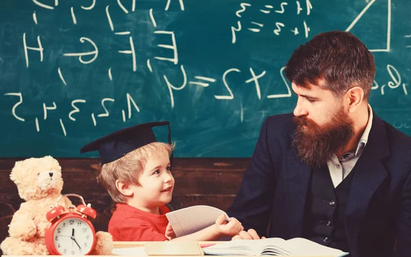 Çocuk mutlu çalışmalar öğretmen, evde ile ayrı ayrı. Bireysel eğitim kavramı. Sakal, oğlum, küçük çocuk öğretmen öğretir Peder. Öğretmen ve öğrenci kolej, kara tahta arka plan içinde