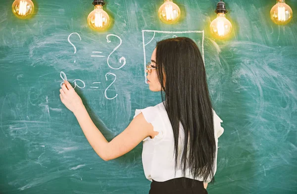 Professor de matemática escrevendo em quadro-negro, visão traseira. Conceito de professor sexy. Senhora professora sexy em óculos explicando fórmula. Mulher com cabelo preto longo ensinando matemática na escola — Fotografia de Stock