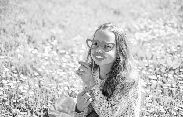 目の前の最初のコンセプトからが大好きです。幸せそうな顔の女の子は、アウトドア レジャーをお過ごしください。草地、緑の背景に芝生の上に女の子が座っています。段ボール ハート型眼鏡でポーズと口を笑顔の子 — ストック写真