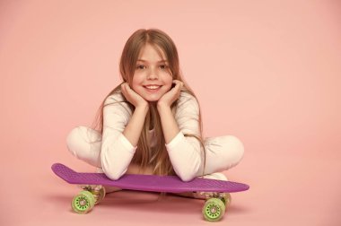 Kaykay çocuk yalan yere pembe bir arka plan üzerine. Çocuk patenci Longboard ile gülümseyen. Küçük bir gülücük ver paten kurulu ile. Çocukluk yaşam tarzı ve aktif spor. Spor aktivitesi ve enerji, punchy pastel