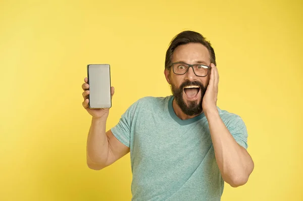 Fantastica applicazione. Occhiali Guy sopraffatti da una nuova applicazione per smartphone. Uomo barbuto utente felice o sviluppatore consiglia di provare smartphone applicazione. L'uomo approfitta della comunicazione online — Foto Stock