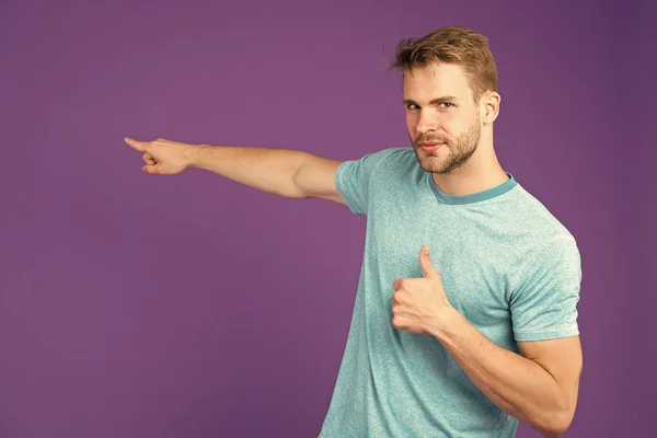 Muy recomendable apuntar con el dedo índice. El hombre sin afeitar la cara muestra pulgares hacia arriba gesto violeta fondo. Hombre satisfecho cara recomiendan mostrar la dirección correcta. El tipo aprueba esa dirección — Foto de Stock