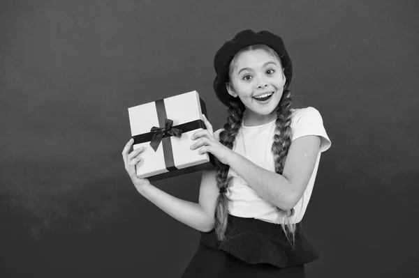 最好的圣诞礼物孩子为打开她的礼物而兴奋。孩子小女孩拿着礼物盒与丝带在红色背景。给女儿的圣诞礼物。可爱的小女孩收到节日礼物 — 图库照片