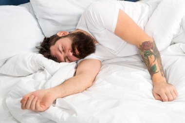 Çok yorgunum. yatak odasında acımasız uykulu adam. yatakta pijama sakallı olgun erkek. enerji ve yorgunluk. uykuda ve uyanık. sakallı adam hipster sabah uyku. Bugün çok yorgun.