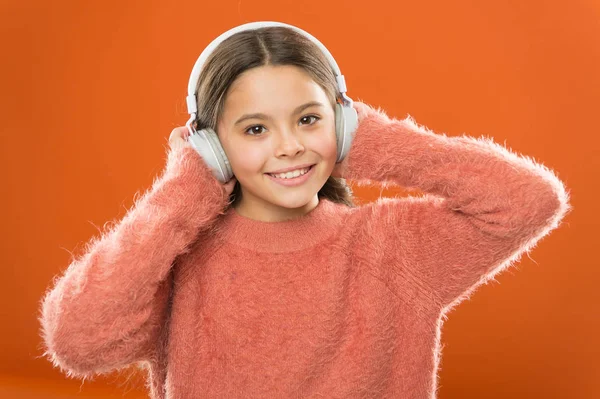 Der einfachste Weg, neue Musik zu finden, die Songs ähnelt, die man bereits liebt. Mädchen niedlichen kleinen Kind tragen Kopfhörer Musik hören. Kind hört Musik orange Hintergrund. Empfohlene Musik basierend auf anfänglichem Interesse — Stockfoto