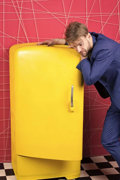 Man formal elegant suit stand near retro vintage yellow refrigerator. Vintage household appliances. Bachelor hungry think what eat near fridge. Bright fridge household appliances. Hunger and appetite