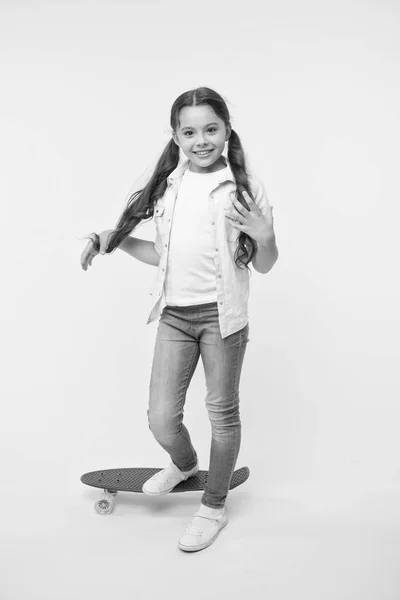 子供の笑顔はスケート ボードの上に立ちます。ペニーは、女の子のためのかわいいカラフルなスケート ボードをボードします。乗ることができます。女の子に乗るペニー ボード黄色背景。子供ペニー ボードを楽しんでいます。趣味のお気に入りの活動 — ストック写真