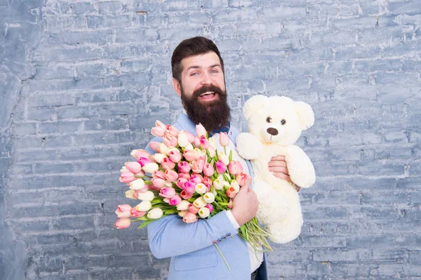 Man wear blue tuxedo bow tie hold flowers bouquet. International womens day. Surprise will melt her heart. Romantic man with flowers and teddy bear. Romantic gift. Macho getting ready romantic date — Stock Photo, Image