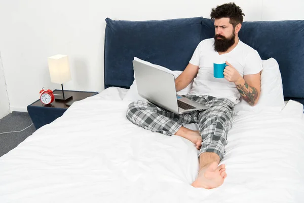 Quick chat at the morning. Taking a break. Too much work. Giving all his energy to work. businessman with computer. bearded man work on laptop. man in bedroom drink coffee. energy and tiredness