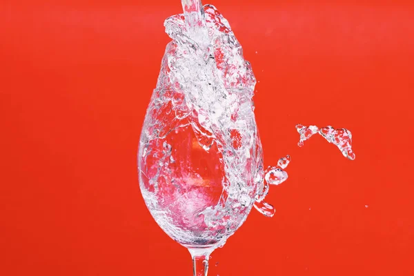 Respingo de água no copo de vinho no fundo vermelho, side vie — Fotografia de Stock