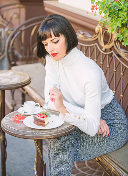 Приятное время и отдых. Изысканная концепция. Вкусный торт для гурманов. Женщина привлекательная брюнетка есть изысканный торт кафе терраса фоне. Гастрономическое наслаждение. Кафе-релакс с тортом
