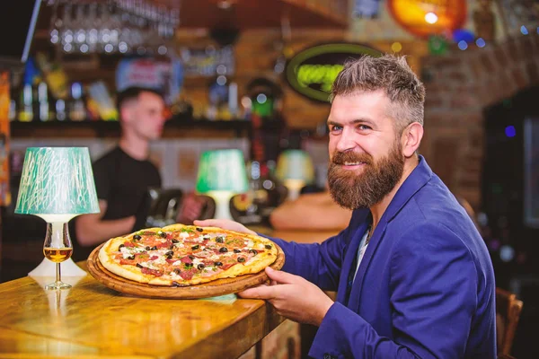 Hipster client sit at bar counter. Man received delicious pizza. Enjoy your meal. Cheat meal concept. Hipster hungry eat italian pizza. Pizza favorite restaurant food. Fresh hot pizza for dinner