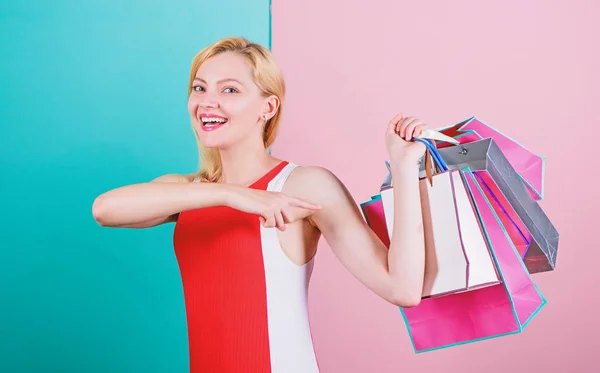 Tips om succesvol te winkelen. Koop alles wat je wilt. Meisje tevreden met winkelen. Meisje houdt van winkelen of net verjaardagscadeaus gekregen. vrouw rood jurk houden bos winkelen tassen blauw roze achtergrond — Stockfoto