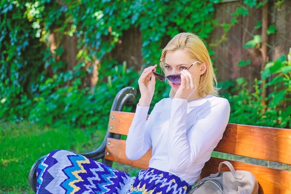 Девушка сидеть скамейка отдыха в тени, зеленый фон природы. Блондинка в солнечных очках мечтает об отпуске, отдыхает в парке. Леди нужно расслабиться и отдохнуть. Время для себя — стоковое фото