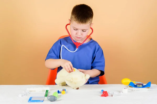 Opieka zdrowotna. Kid mały lekarz zajęty siedzieć stół z narzędziami medycznymi. Lekarskie. Koncepcja medycyny. Zabiegi medyczne na misia. Chłopiec Cute dziecko przyszłej kariery lekarza. Pracownik szpitala — Zdjęcie stockowe