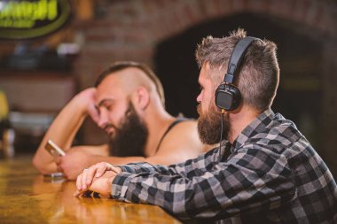 Gerçeklikten kaç. Barda cuma günü dinlenmek. Hipster sakallı adam bar tezgahında boş vakit geçiriyor. Bar tezgahında içki ısmarla. Kulaklıklı ve akıllı telefonu olan erkekler barda dinleniyor. İletişimden kaçının
