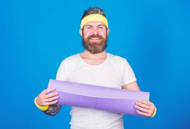 Adam atlet tutun fitness mat mavi renkli sakallı. Yoga sınıfında bir başlangıç sağlar. Yoga hobi ve spor olarak. Her gün pratik yoga. Formda kalmak. Atlet profesyonel yoga koç eğitim için motive