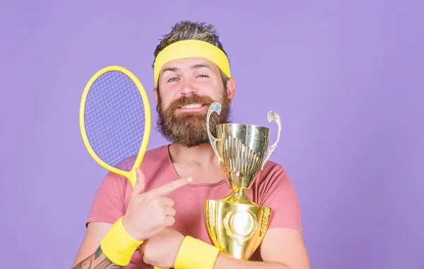 First place. Sport achievement. Tennis champion. Win tennis game. Celebrate victory. Athletic man hold tennis racket and golden goblet. Tennis player win championship. Man bearded successful athlete