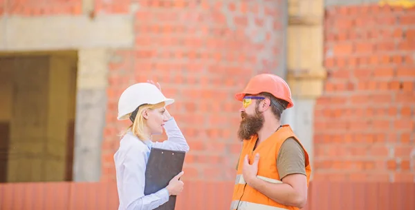 Construction site safety inspection. Discuss progress project. Construction project inspecting. Safety inspector concept. Woman inspector and bearded brutal builder discuss construction progress