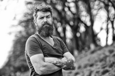Hipster emin tutun çarpı işareti kollar göğüs üzerinde sakallı. Sakallı hippi acımasız maço. Kuaför kavramı. Bıyık ciddi bir yüz emin doğa arka plan ile sakallı adam. Gözlüklü sakallı adam