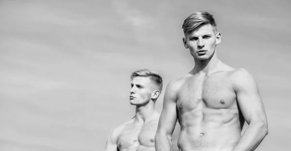 Masculinity concept. Attractive muscular twins. Muscular healthy athletic body. Men twins brothers muscular guys sky background. Sexy torso attractive body. Men strong muscular athlete bodybuilder