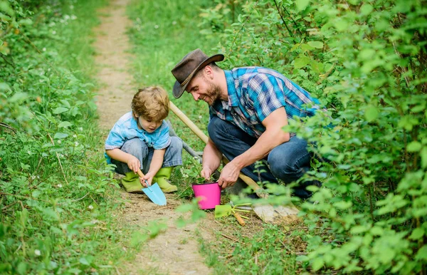 happy earth day. Family tree nursering. father and son in cowboy hat on ranch. hoe, pot and shovel. Garden equipment. Eco farm. small boy child help father in farming. Horticulture activities