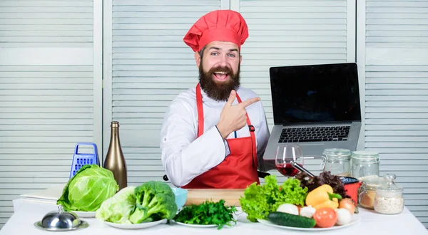 ELearning-konceptet. laptop läsa kulinariska recept. Kulinariska skolan. Hipster i hatt och förkläde lära sig att laga mat på nätet. Kulinarisk utbildning på nätet. Man söker Internet recept Matlagning mat — Stockfoto