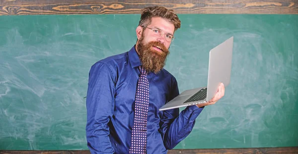 Hipster professeur porter des lunettes et cravate détient ordinateur portable surfer sur Internet. Concept d'enseignement à distance. Professeur barbu homme avec ordinateur portable moderne surf internet tableau arrière-plan. Surfer sur internet — Photo