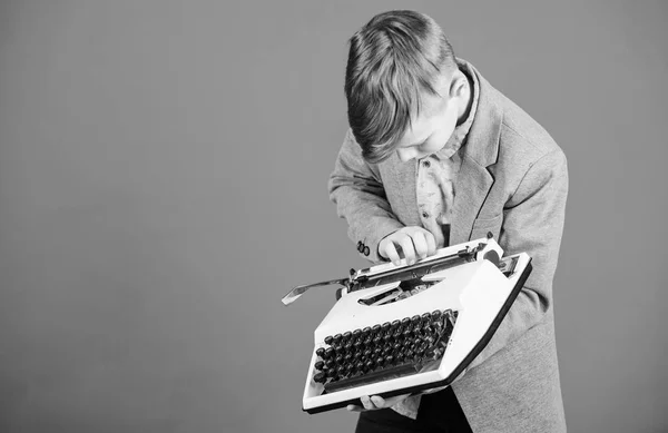 Yazarak makinasıyla. Küçük çocuk üzerinde eski daktilo typewriting. Vintage daktilo ile akıllı okul çocuğu. Daktilo ile sevimli çocuk. Küçük çocuk holding retro daktiloda mavi arka plan, kopya alanı — Stok fotoğraf