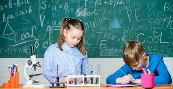 Análisis químico. Niños ocupados estudiando química. Lección de química escolar. Laboratorio escolar. Estudiantes inteligentes de niñas y niños llevan a cabo experimentos escolares. Describa el bloc de notas de reacción química. Educación escolar — Foto de Stock