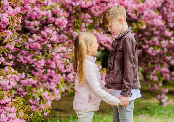 恋に落ちる春。愛のピンクの桜の子供たち。愛は空中にある。カップル愛らしい素敵な子供たちが桜の庭を歩きます。優しい愛の気持ち。小さな女の子と男の子公園でロマンチックなデート — ストック写真