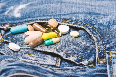 Uyuşturucu denim arka plan üzerinde. İlaçlar karıştırma. Hızlı tedavi. İlaç reçete. Sağlık ve hastalık. Doz ve bağımlılığı. Uyuşturucu bağımlılığı. Renkli hapları kümesi. İlaç ve tedavi kavramı