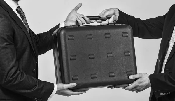 Business transfer concept. Male hand hold briefcase. Handover of case in hands of business partners. Handover of illegal goods. Illegal deal handover. Hands give briefcase for exchange or offer bribe