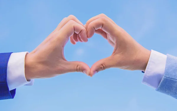 Hands put together in heart shape blue sky background. Hand heart gesture forms shape using fingers. Male hands in heart shape gesture symbol of love and romance. Love symbol concept