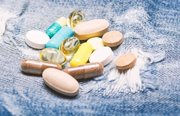 Health care and illness. Dose and addiction. Drug addiction. Medicine and treatment concept. Drugs on denim background. Set of colorful pills. Mixing medicines. Fast treatment. Medicine prescription