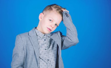 Şık ve kendinden emin. Moda ufaklikla ciddi bakın. Saçları dokunmadan yakışıklı çocuk. Çok güzel okul öncesi çocuk veya resmi aşınmaya okul çocuğu. Mavi arka plan üzerinde küçük çocuk