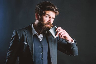 Akşamdan kalma. Uzun çalışma günü. Takım elbiseli bir iş adamı. acımasız beyaz hipster kötü bağımlılığı var. Sakallı olgun hipster şişesi cebine koydu. Lisans ve tek. Sakallı adam içki alkol