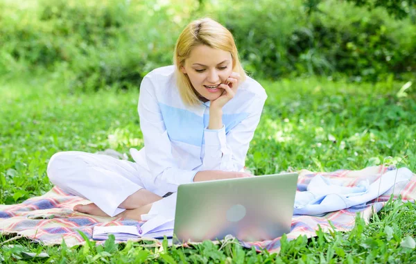 İş pikniği kavramı. Serbest çalışmaya başlamak için adımlar. Dizüstü bilgisayarı ya da defteri olan bir kadın yeşil çimlerin üzerinde oturuyor. İş kadını serbest çalışan biri dışarıda çalışıyor. Çevrimiçi iş fikirleri kavramı