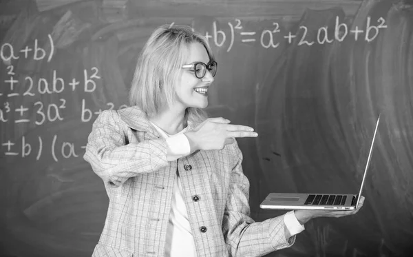 Vrouw houdt laptop wijzen met wapen gebaar op scherm. Opvoeder slimme slimme dame met moderne laptop houden pistool gebaar schoolbord achtergrond. Educatieve hervormingen concept. Informatie over haar doel — Stockfoto