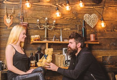 Gülümseyen yüzler üzerinde aşık çift tatilin keyfini çıkarın. Çift gamekeepers evde, ahşap iç arka plan romantik akşamın. Adam Bayan oyuncak ayı için yıldönümü hediye olarak vermek. Yıldönümü kavramı