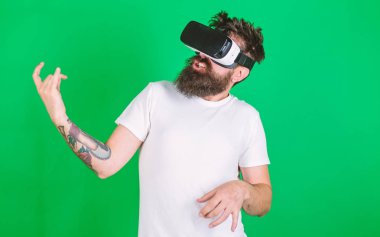 Hipster gitarist hevesli yüzündeki modern teknoloji eğlence için kullanın. Vr gözlüklü öğrenin gitar müzik çalmak. VR müzisyen kavramı. Vr gözlük, yeşil arka planda sakallı