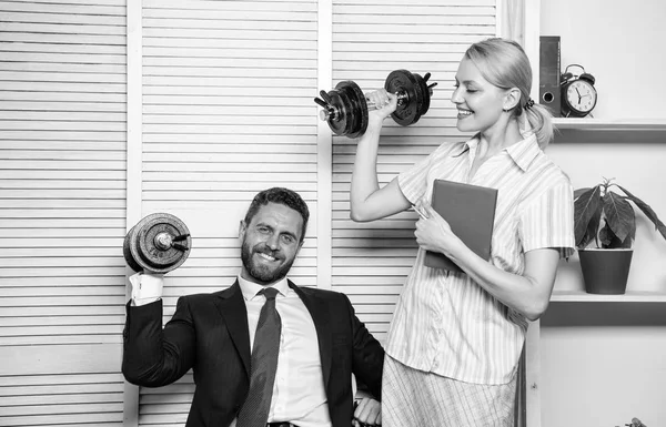 Man and woman raise heavy dumbbells. Strong powerful business strategy. Good job concept. Boss businessman and office manager raise hand with dumbbells. Strong business team. Healthy habits in office