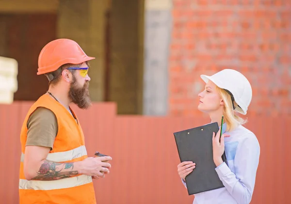 Relationships construction client and participant building industry. Discuss progress plan. Woman engineer and bearded brutal builder discuss construction progress. Construction industry concept