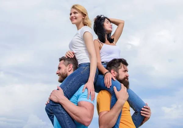 Taking real pleasure. Playful couples in love smiling on cloudy sky. Loving couples having fun activities outdoor. Loving couples enjoy fun together. Happy men piggybacking their girlfriends — Stock Photo, Image