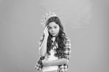 Prenses olmak çok zor. Tatlı kız mavi arka planda dururken taç takıyor. Çocukluk konsepti. Rüya gören her kız prenses olur. Küçük hanım prenses. Çocuk prensesin altın taç sembolünü takıyor.