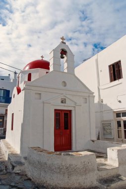 Mykonos, Yunanistan'ın bina Kilisesi. Şapel çan kulesi ve kırmızı kubbe ile. Bulutlu gökyüzü beyaz Kilise mimarisi. Yaz tatili bir Akdeniz Adası, yolculuk tutkusu. Din ve kült kavramı