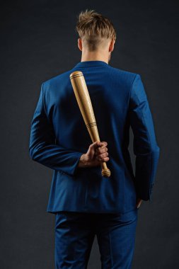 Gizli saldırganlık. İş adamı ya da resmi takım elbiseli bir adam arkasında tahta bir sopa saklıyor. Gizli tehlike kavramı. Beyzbol sopalı adam saldırganlığını gizler. Yavaşla ve sakin ol.