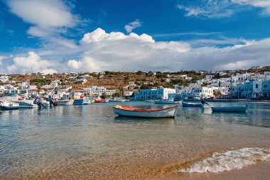 Mykonos, Yunanistan - 04 Mayıs 2010: deniz suyu gemilerde. Deniz kumsalda bulutlu mavi gökyüzü. Dağ manzarası ile Akdeniz mimari evler. Adada tatil yaz. Yolculuk tutkusu ve seyahat