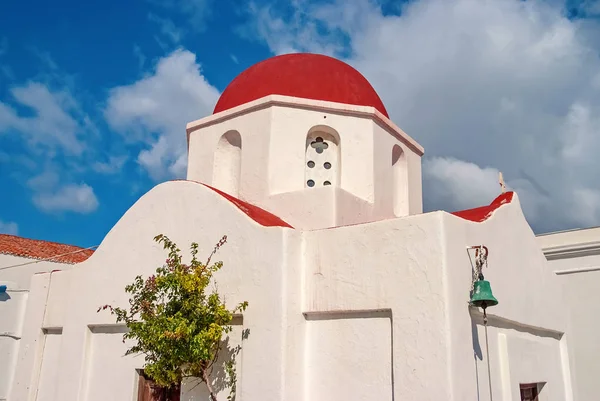 Church with red dome in Mykonos, Greece. Chapel building architecture on sunny outdoor. White church on cloudy blue sky. Summer vacation on mediterranean island, wanderlust. Religion and cult concept — Stock Photo, Image