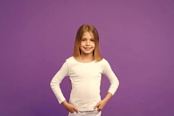 笑顔長い髪の少女は、紫色の背景の白いシャツを着ています。女の子は、おしゃれに空間をコピーが好きです。長い髪の子供女の子に見える愛らしい。ファッションや服のコンセプト — ストック写真